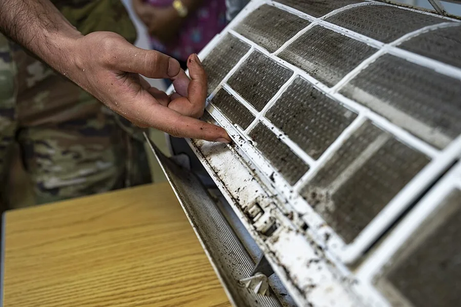 Technician inspecting the dirty filter of an air conditioning unit