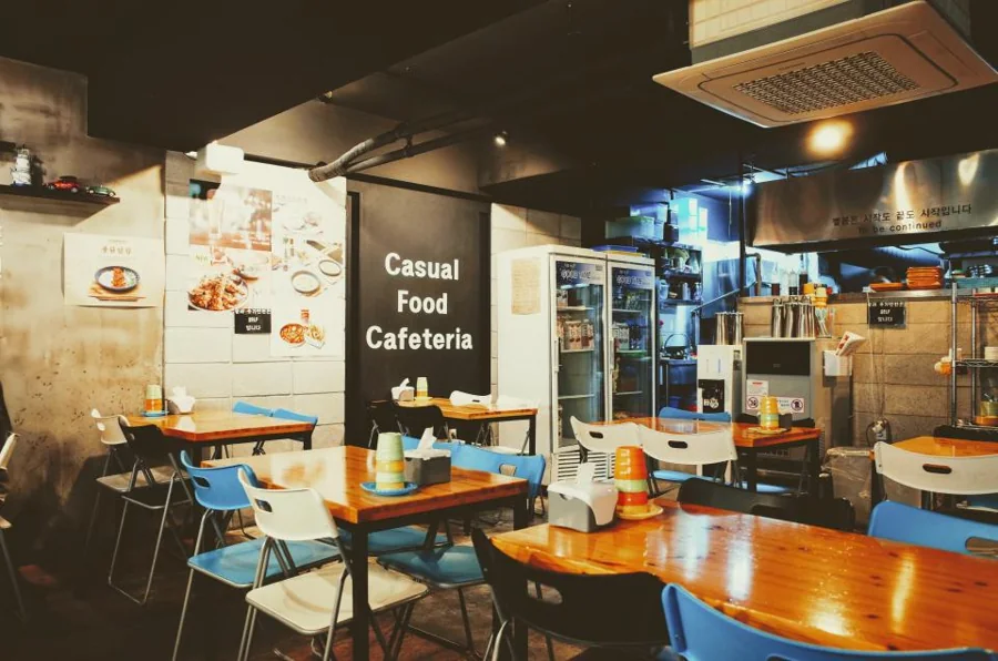 Small restaurant dining room with glass-door refrigerators in the back